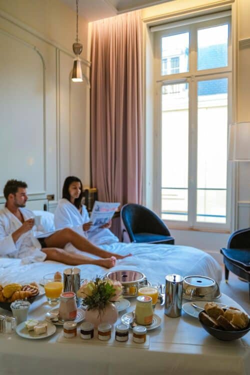 morning wake up in bed in paris with breakfast coffee and a newspaper,men and woman honymoon