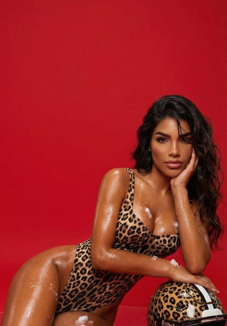 Woman in leopard print swimsuit and helmet, red background.