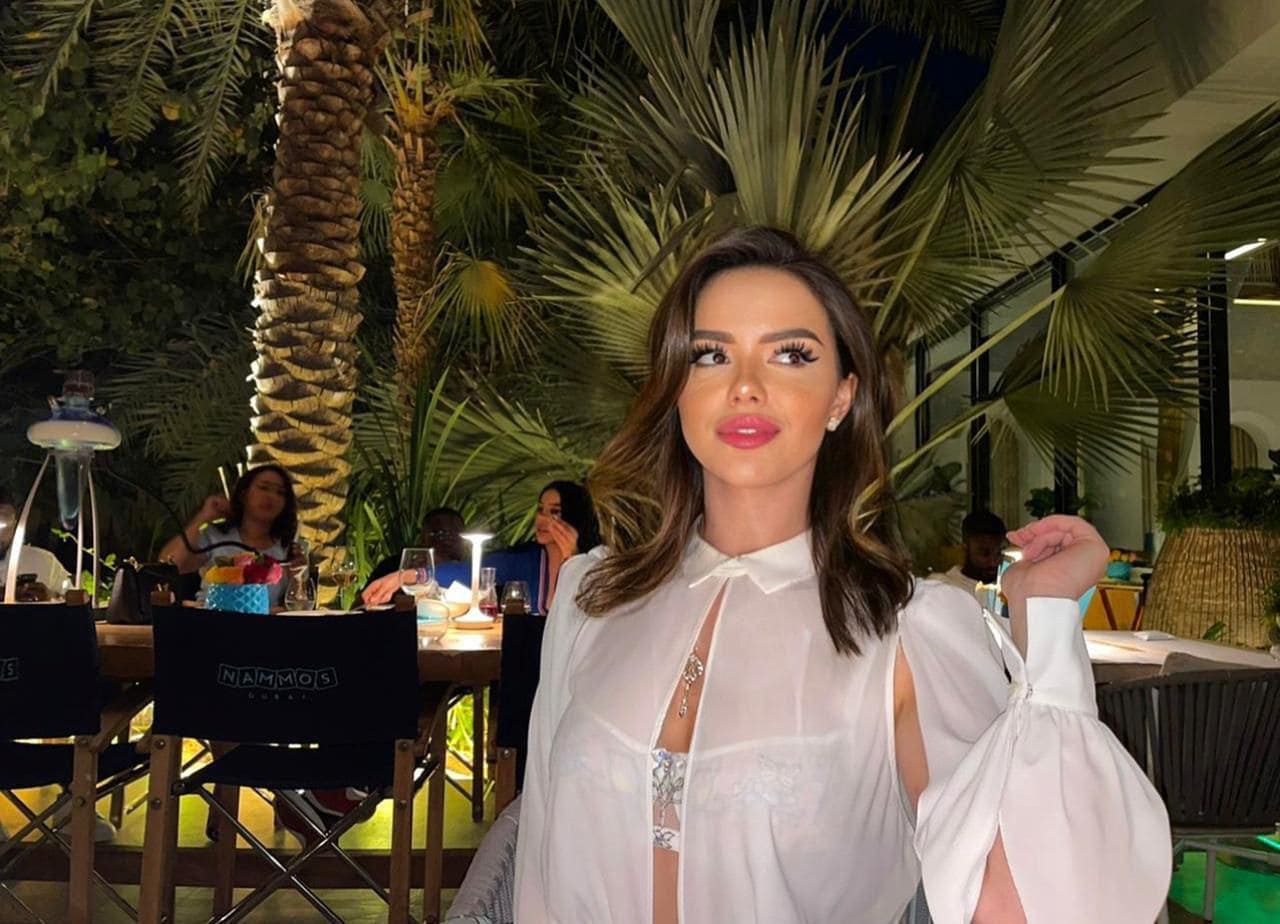 Woman in white blouse posing at night outdoor restaurant.