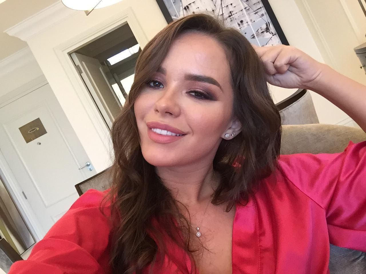 Smiling woman with brown hair wearing a pink silk robe.