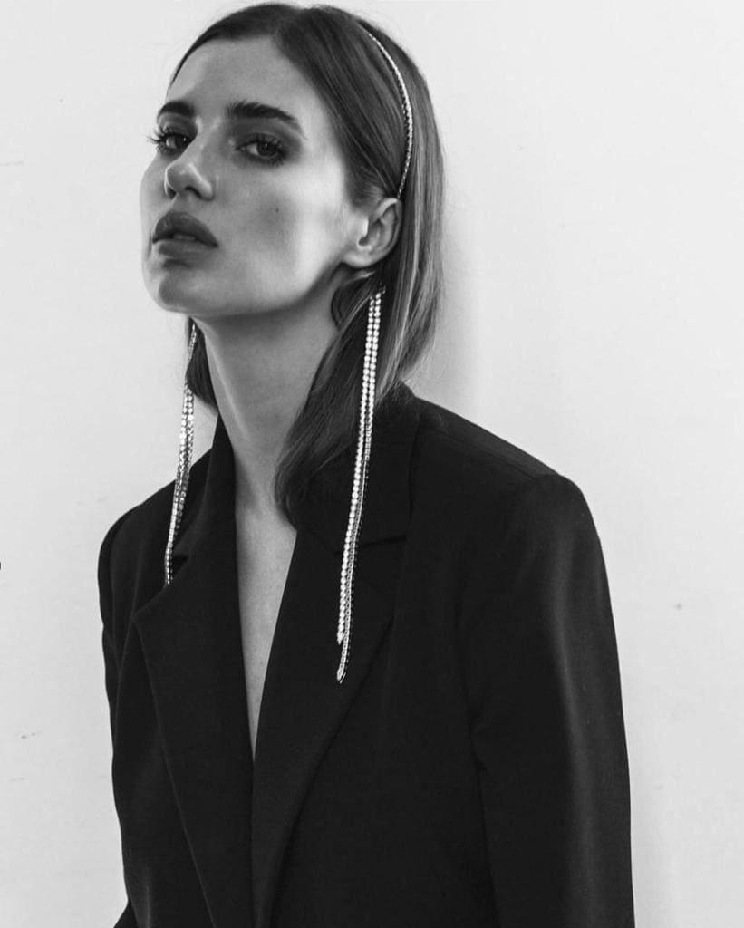 Woman in black blazer with long earrings.