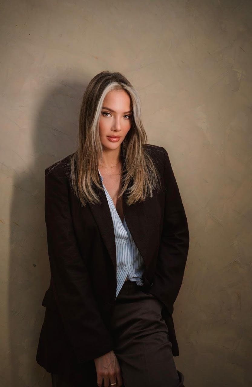 Woman with face-framing blonde highlights in a dark blazer.