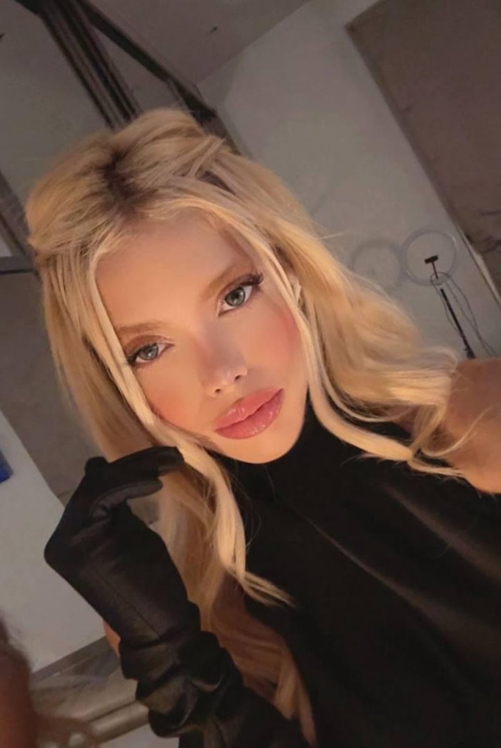 Blonde woman wearing long black gloves and high-neck top.