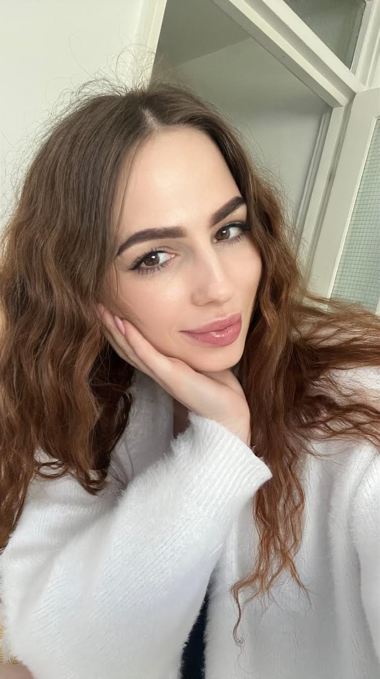 Woman with long wavy hair resting chin on hand.