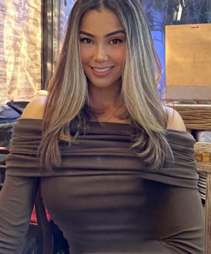 Woman with long highlighted hair smiling in a restaurant.