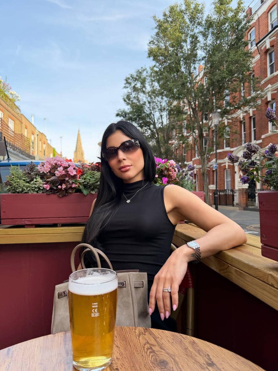 Woman sitting outdoors at a pub with a pint.