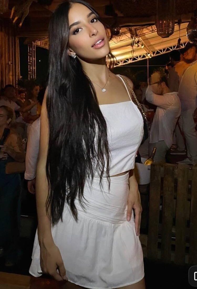 Young woman with long dark hair in a white outfit.
