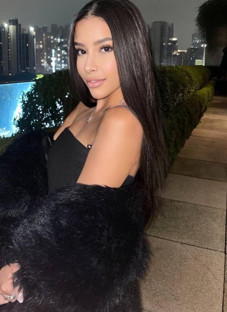 Glamorous woman with long dark hair posing against city skyline.