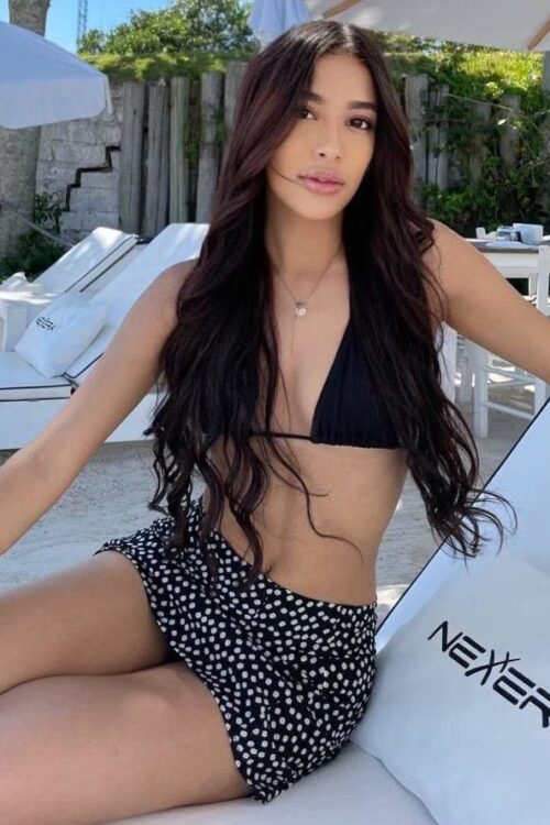 Woman in black bikini and floral skirt at a resort.