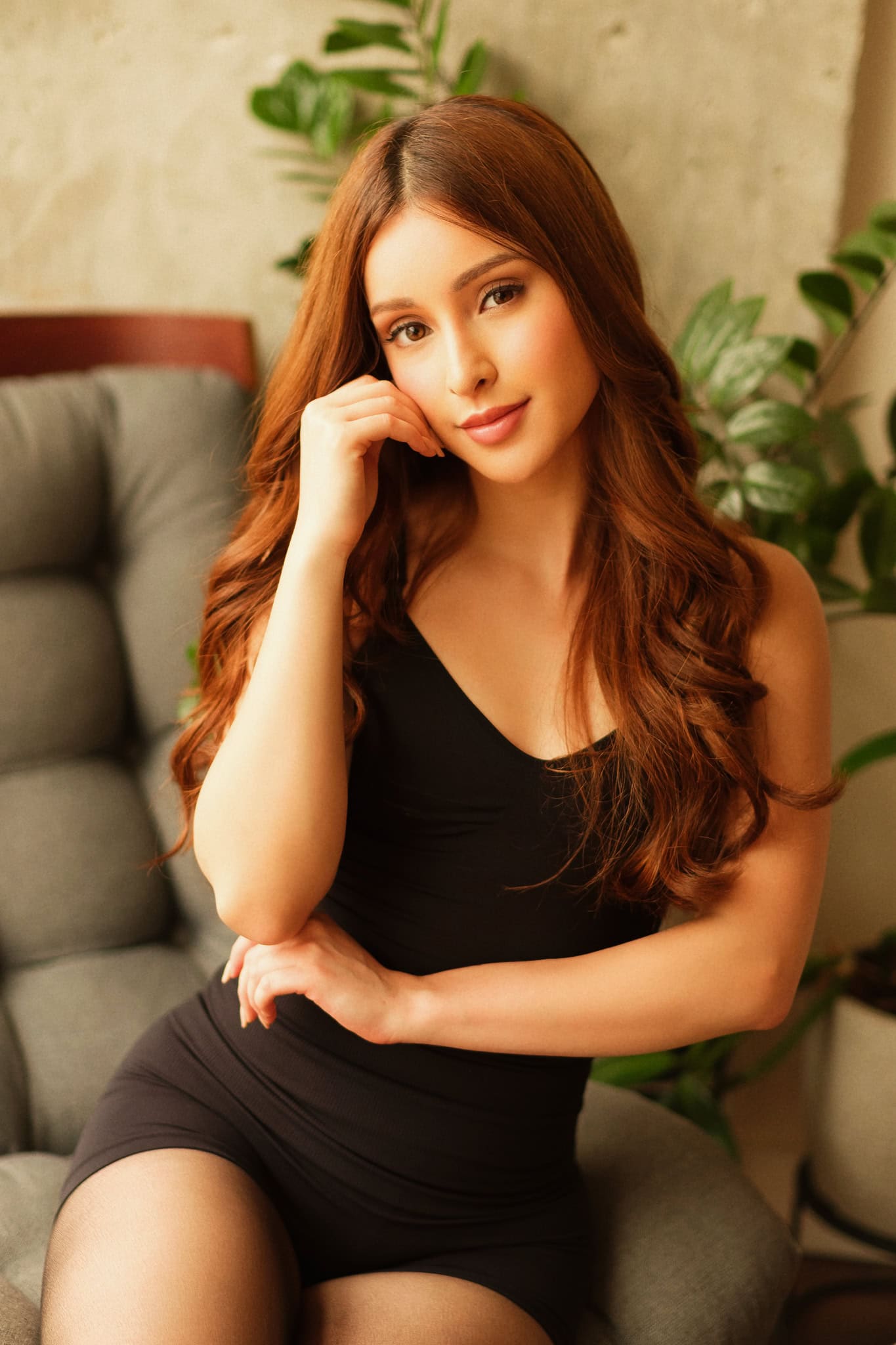 Woman with long wavy auburn hair in black bodysuit.