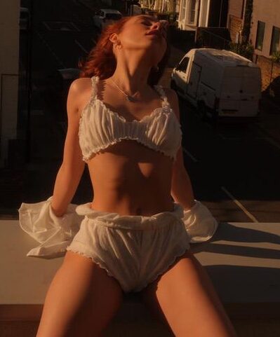 Woman in white ruffles basking in golden hour rooftop sun.