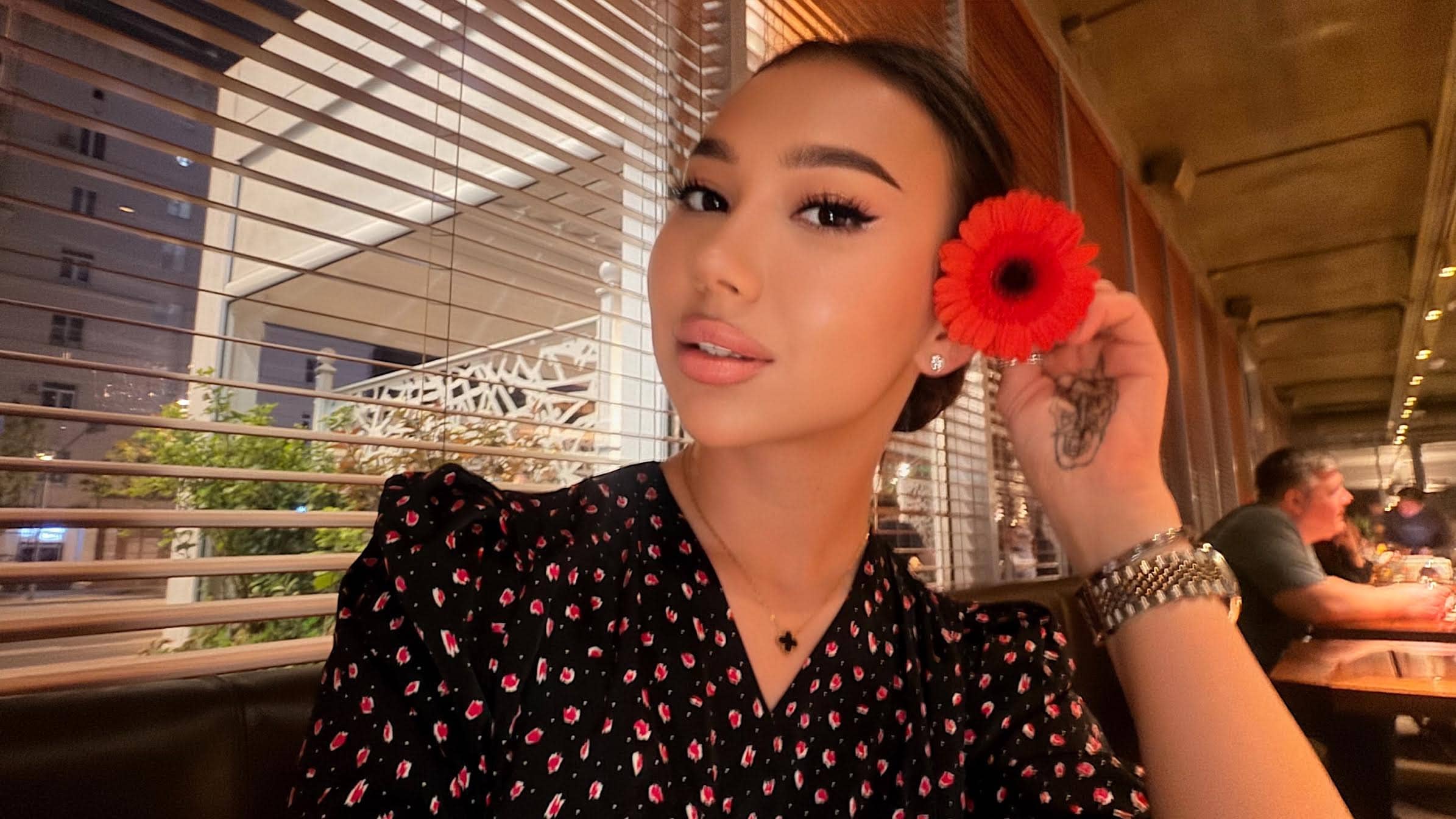 A woman posing with a red flower behind her ear.