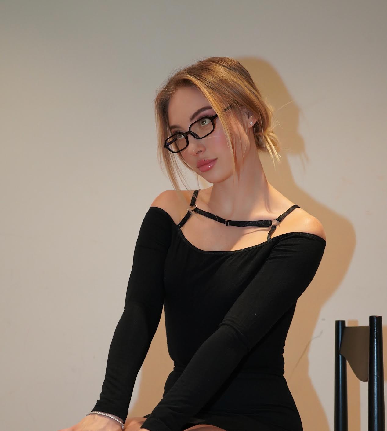 Woman in black glasses and black top looking away.