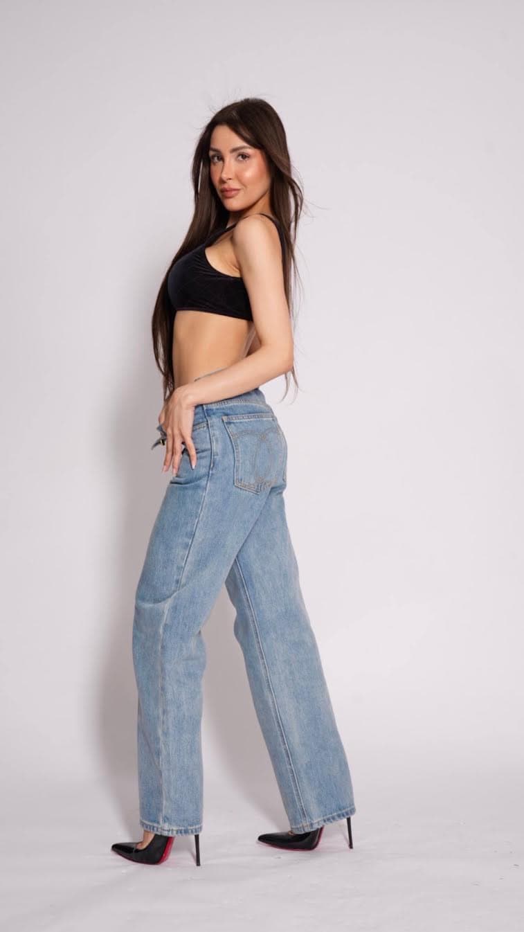 Woman posing in black crop top and light blue jeans.