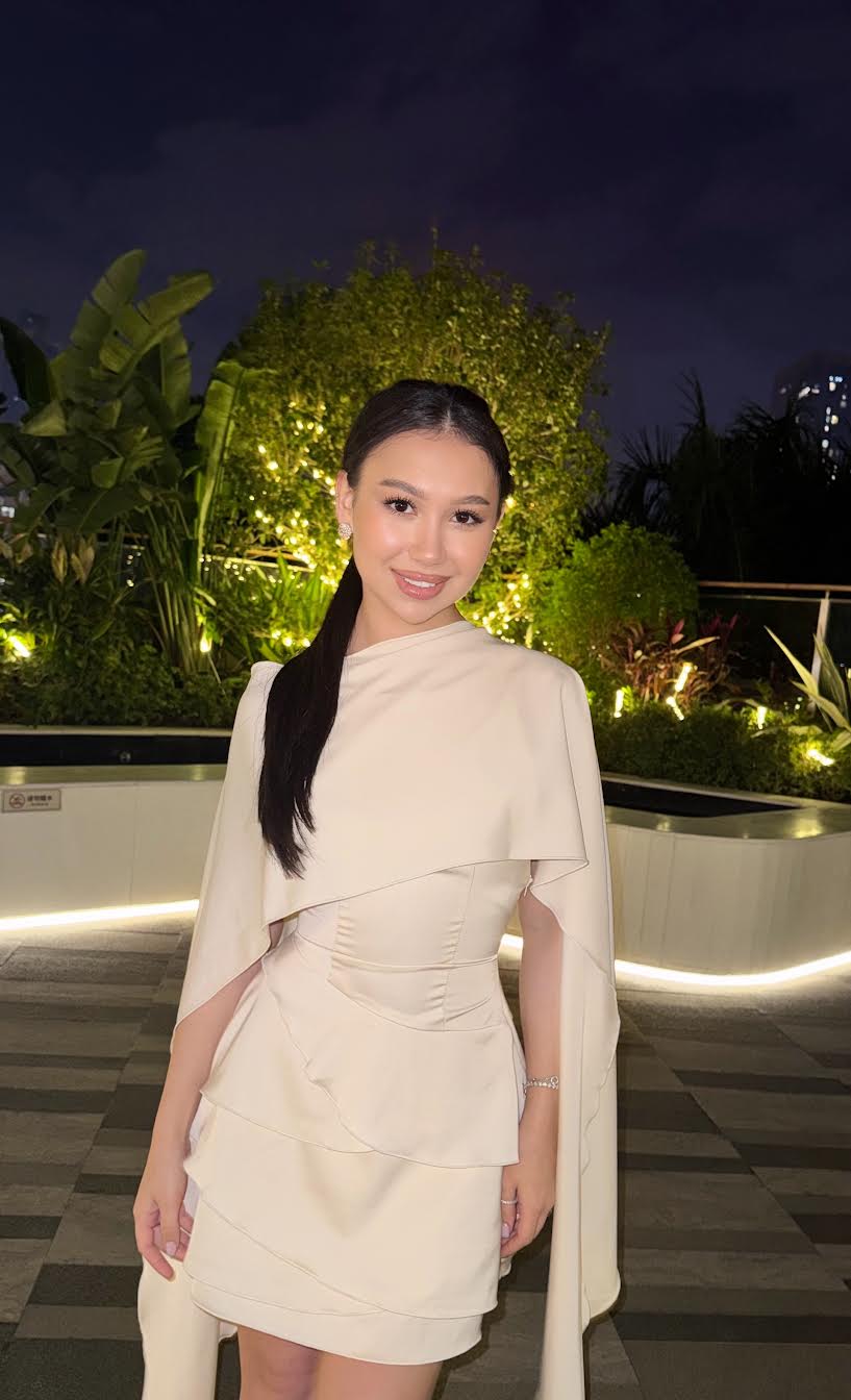 Woman in an elegant cream cape-style dress at night.