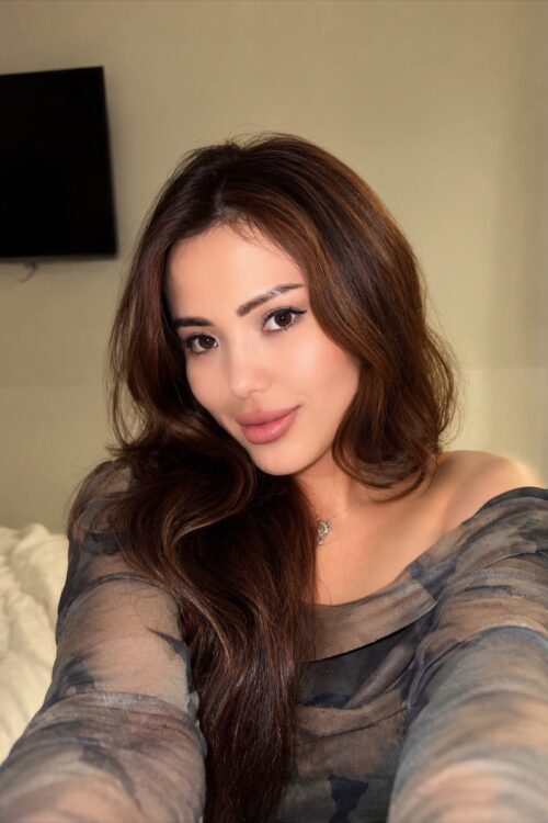 Woman with long brown hair in off-the-shoulder top.