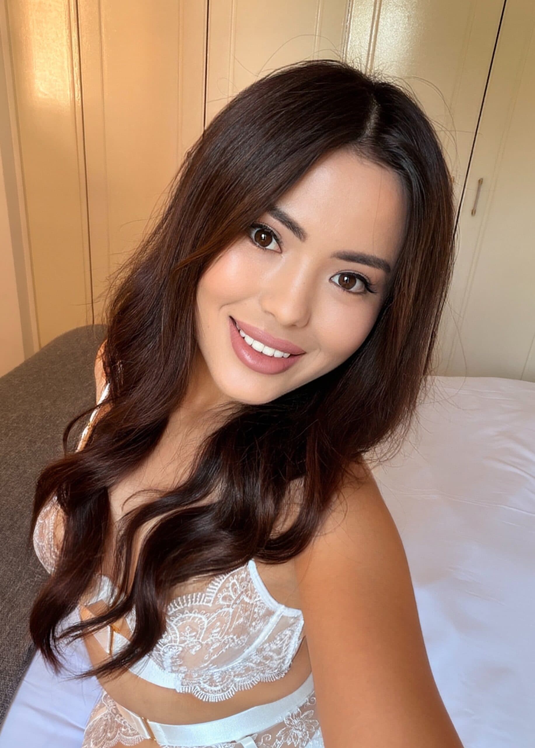 Young woman with long dark hair smiling in lace lingerie.