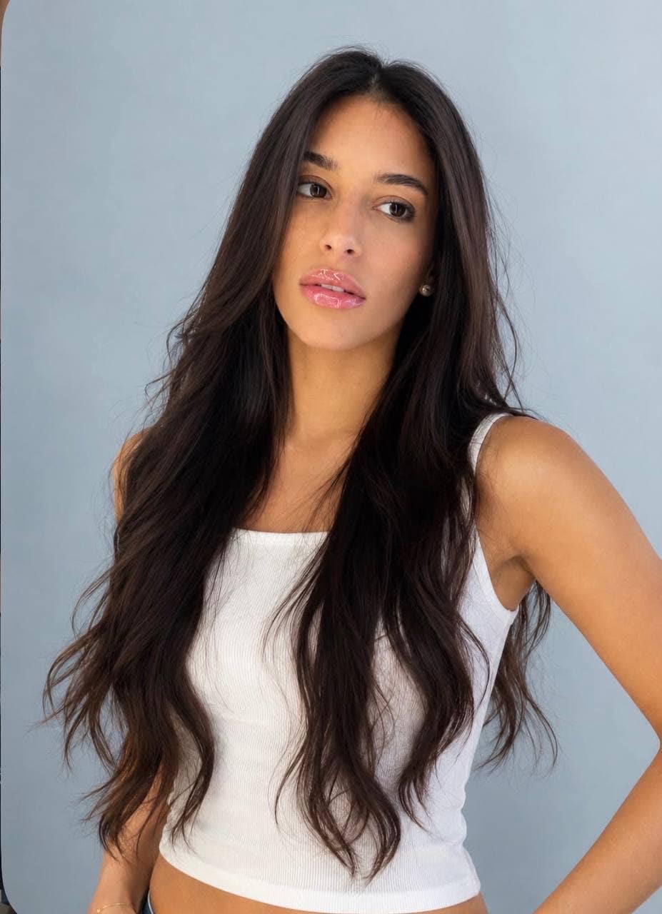 Woman with long dark wavy hair in white top.