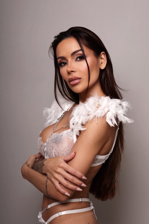 Woman in white lace lingerie with feather shoulder details.