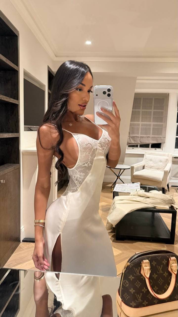Woman in white lace slip dress taking a mirror selfie.