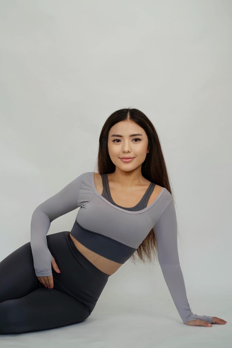 Woman in grey activewear set posing against a white background.