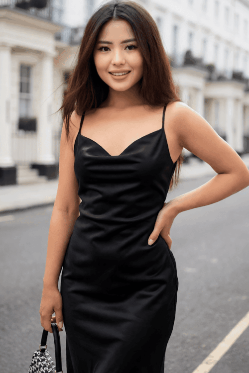 Woman in black satin dress posing on a London street.
