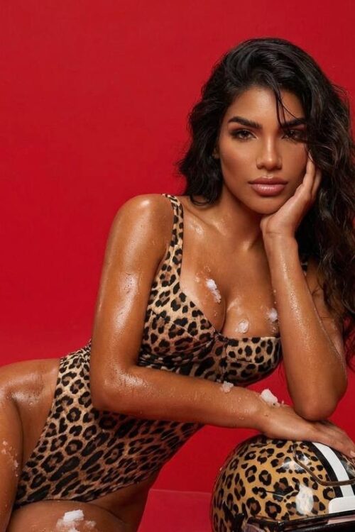 Woman in leopard bodysuit leaning on a leopard football helmet.